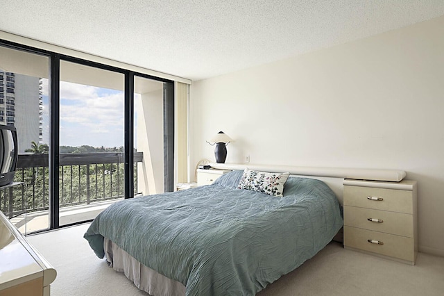 bedroom featuring access to outside, a textured ceiling, floor to ceiling windows, and light carpet