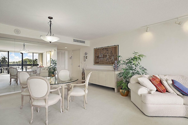 dining space with track lighting, a textured ceiling, visible vents, and light carpet