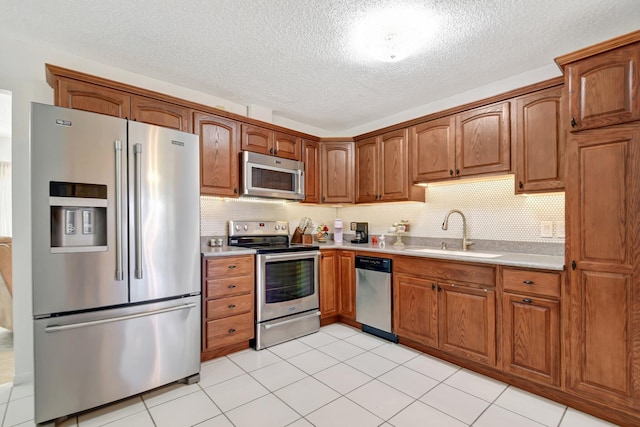 245 Bilbao St, Royal Palm Beach, FL 33411 - kitchen featuring stainless steel appliances, a sink, light countertops, a textured ceiling, and brown cabinets