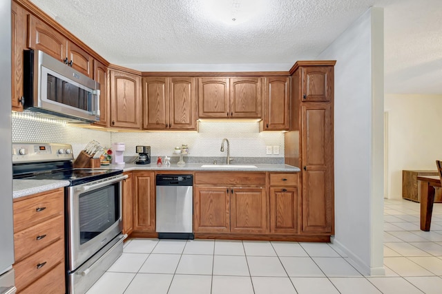 245 Bilbao St, Royal Palm Beach, FL 33411 - kitchen with stainless steel appliances, a sink, light countertops, a textured ceiling, and brown cabinets