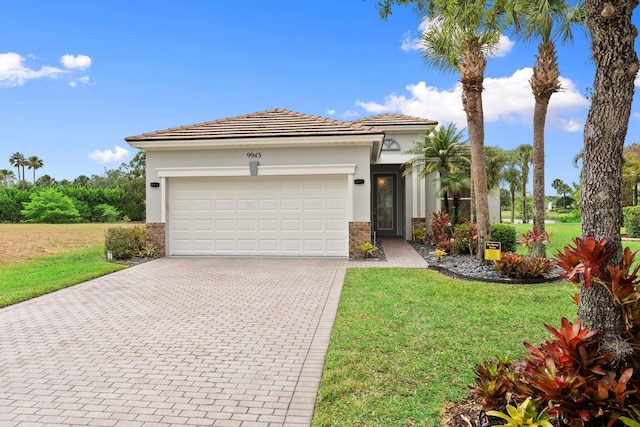 9943 SW Stonegate Dr, Port Saint Lucie, FL 34987 - view of front of property featuring driveway, a front lawn, an attached garage, stucco siding, and stone siding