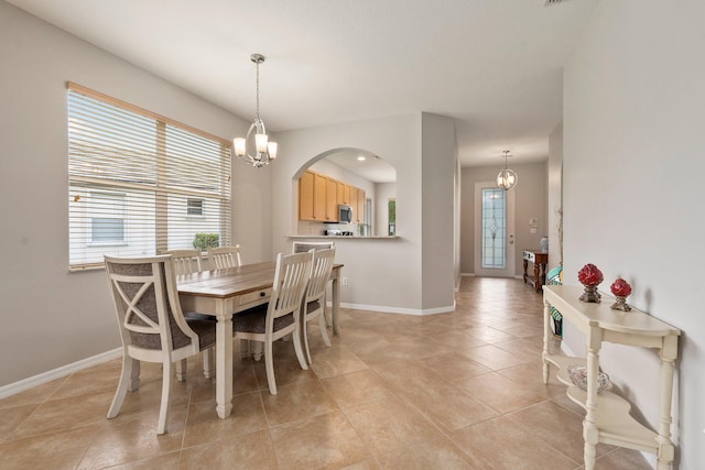 9943 SW Stonegate Dr, Port Saint Lucie, FL 34987 - dining area featuring a chandelier, arched walkways, baseboards, and light tile patterned floors