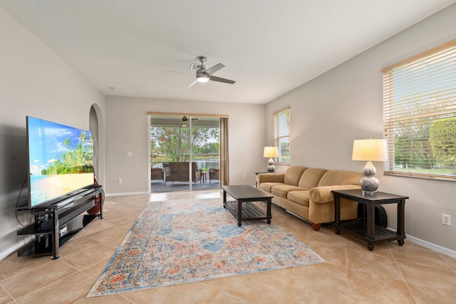 9943 SW Stonegate Dr, Port Saint Lucie, FL 34987 - living room featuring light tile patterned floors, a ceiling fan, baseboards, and arched walkways