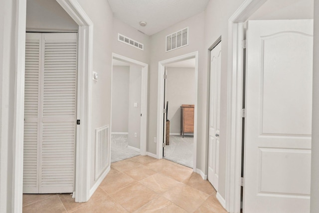 9943 SW Stonegate Dr, Port Saint Lucie, FL 34987 - corridor featuring light tile patterned floors, light colored carpet, and baseboards