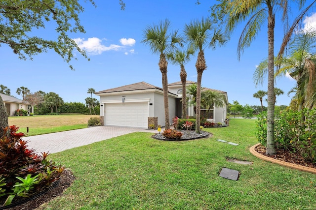 9943 SW Stonegate Dr, Port Saint Lucie, FL 34987 - view of front of home with stucco siding, a garage, decorative driveway, and a front yard