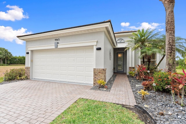 9943 SW Stonegate Dr, Port Saint Lucie, FL 34987 - view of front facade with decorative driveway, stucco siding, an attached garage, and stone siding