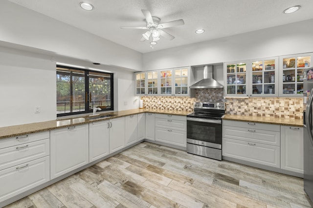 kitchen featuring a ceiling fan, recessed lighting, a sink, wall chimney range hood, and stainless steel appliances