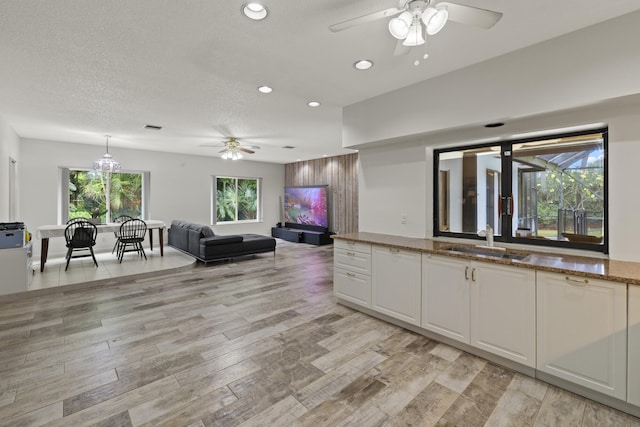 kitchen with a sink, recessed lighting, ceiling fan, white cabinetry, and stone counters