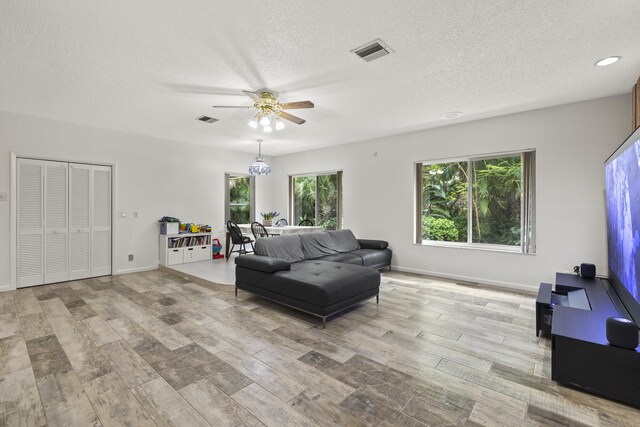 living room with a ceiling fan, visible vents, and plenty of natural light