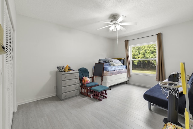 bedroom with baseboards, ceiling fan, a textured ceiling, and wood finished floors