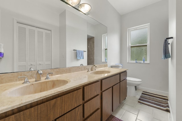 full bathroom with a sink, double vanity, toilet, and tile patterned flooring