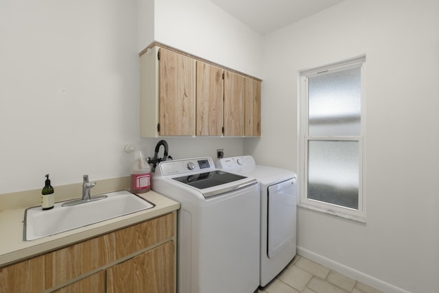 washroom with a sink, cabinet space, separate washer and dryer, baseboards, and light tile patterned flooring