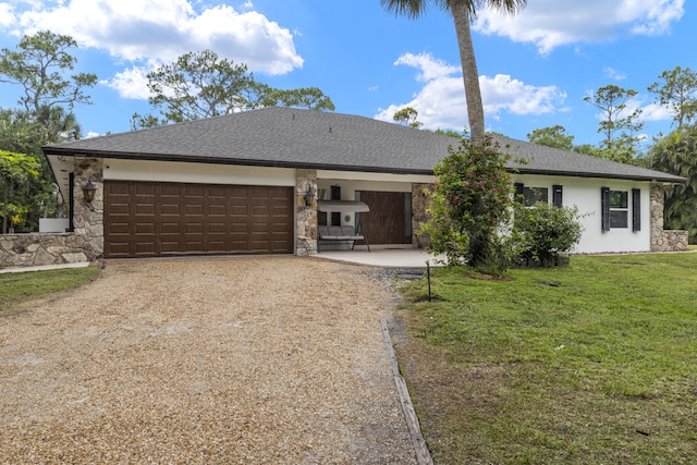 ranch-style home with driveway, an attached garage, stone siding, and a front yard