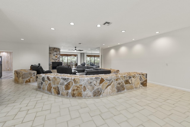 living area with a ceiling fan, a stone fireplace, and recessed lighting