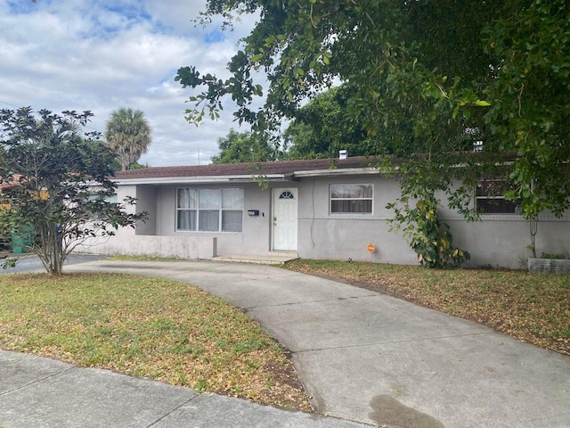 single story home featuring a front lawn, stucco siding, and driveway