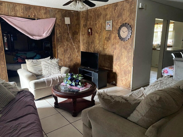 living room with ceiling fan, wood walls, and light tile patterned flooring