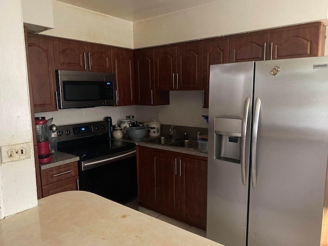 kitchen with light countertops, dark brown cabinets, appliances with stainless steel finishes, and a sink