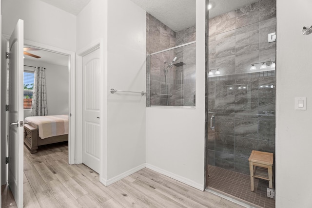 full bath with ensuite bathroom, wood finished floors, ceiling fan, a shower stall, and baseboards