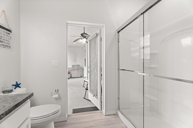 full bathroom featuring a stall shower, baseboards, wood finished floors, and a ceiling fan