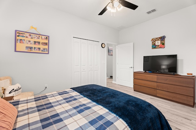 bedroom with a closet, light wood-style floors, visible vents, and ceiling fan