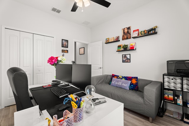 office space with a ceiling fan, light wood finished floors, and visible vents