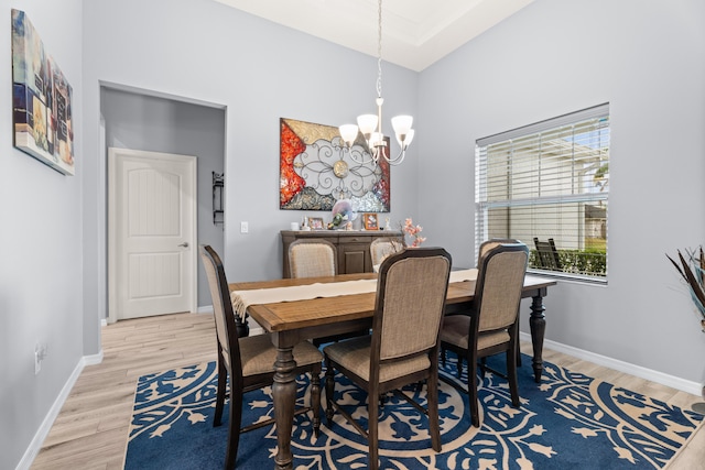 dining space featuring baseboards, a notable chandelier, light wood finished floors, and a high ceiling