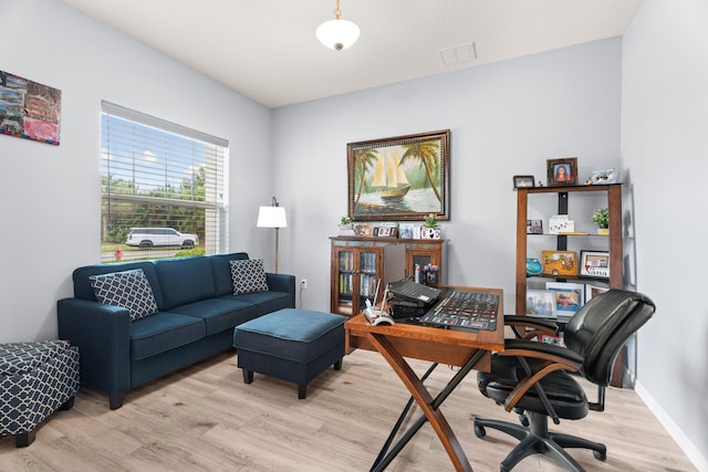 home office with baseboards, light wood finished floors, and visible vents