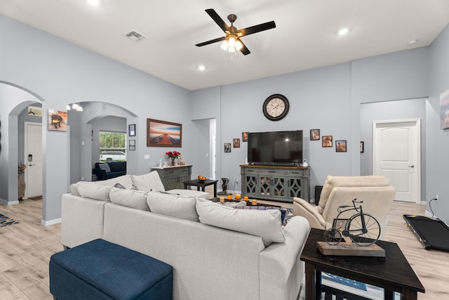 living area featuring ceiling fan, arched walkways, visible vents, and light wood-style floors