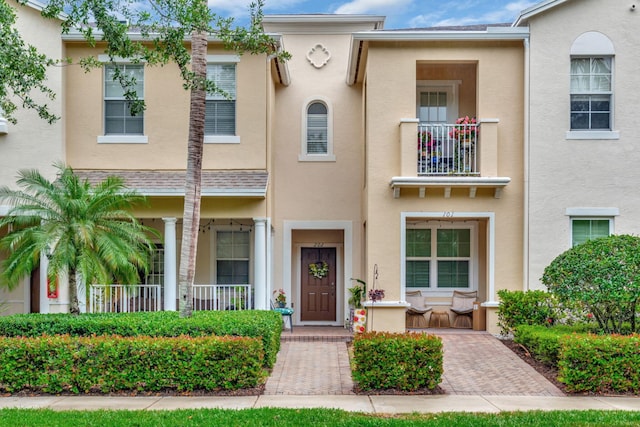 townhome / multi-family property with covered porch and stucco siding