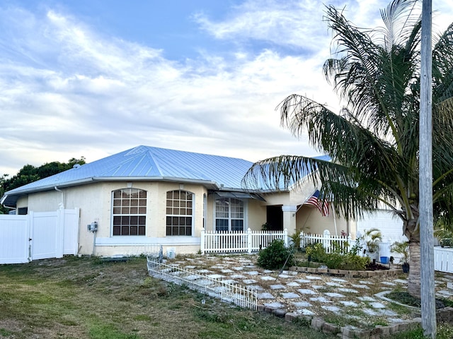 view of front of property with a gate, stucco siding, fence, metal roof, and a porch