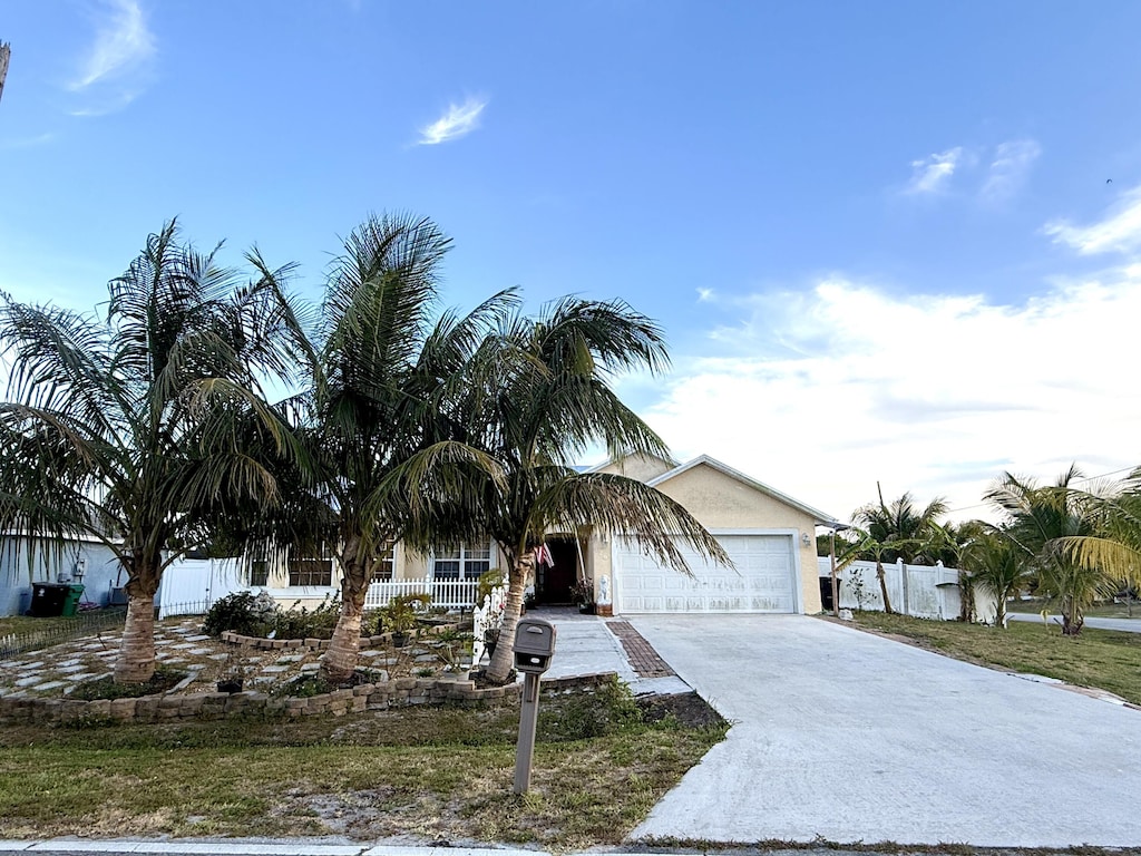 view of front of home featuring fence, a garage, stucco siding, and driveway