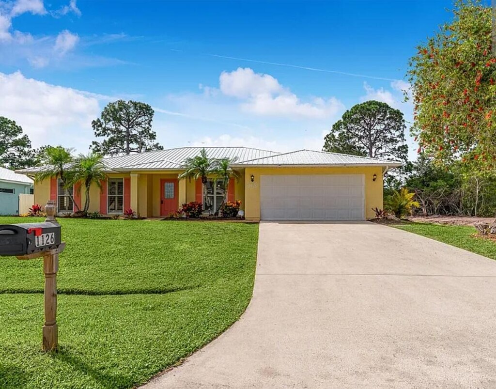 1126 SW Calmar Ave, Port Saint Lucie, FL 34953 - ranch-style house featuring an attached garage, stucco siding, a front yard, a standing seam roof, and driveway