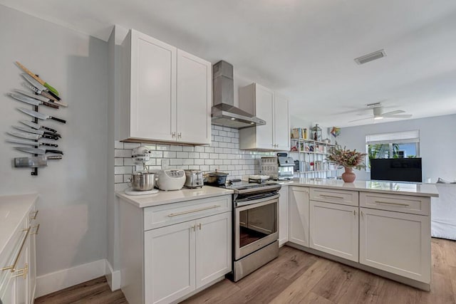 923 N H St, Lake Worth Beach, FL 33460 - kitchen with stainless steel electric range oven, white cabinets, wall chimney exhaust hood, a peninsula, and backsplash