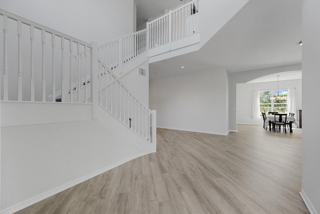 1317 Beacon Cir, Wellington, FL 33414 - unfurnished living room with wood finished floors, arched walkways, baseboards, stairs, and a high ceiling