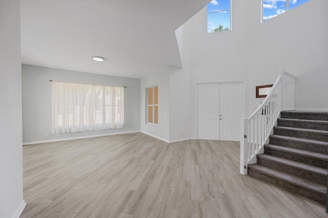 1317 Beacon Cir, Wellington, FL 33414 - unfurnished living room with wood finished floors, stairway, healthy amount of natural light, baseboards, and a towering ceiling