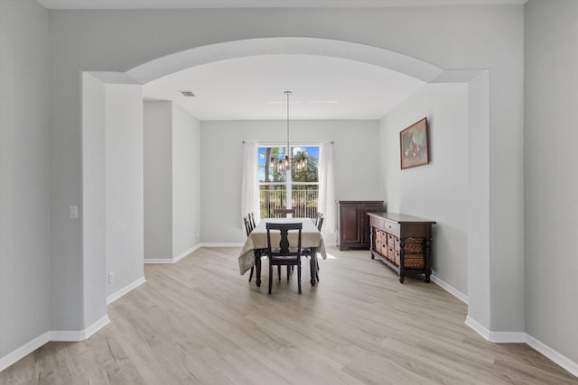 1317 Beacon Cir, Wellington, FL 33414 - dining room with arched walkways, light wood-style floors, a chandelier, and baseboards