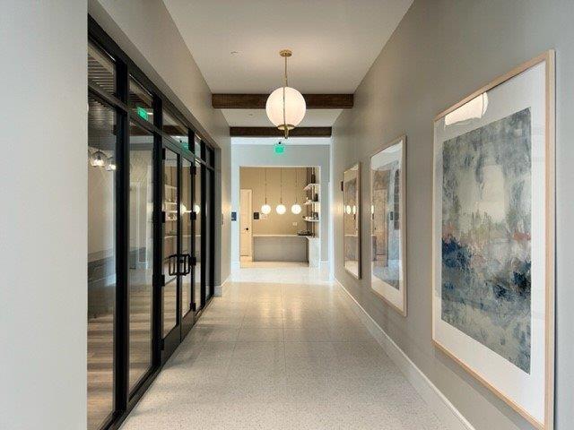 hallway featuring french doors, baseboards, speckled floor, and beam ceiling