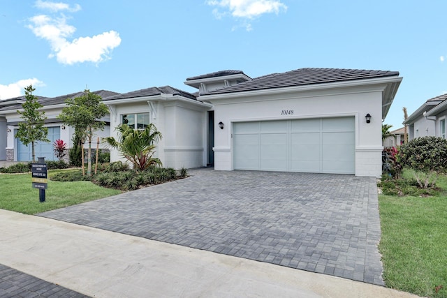 10148 Driftwood Way, Palm Beach Gardens, FL 33412 - prairie-style home featuring driveway, an attached garage, a front lawn, and stucco siding