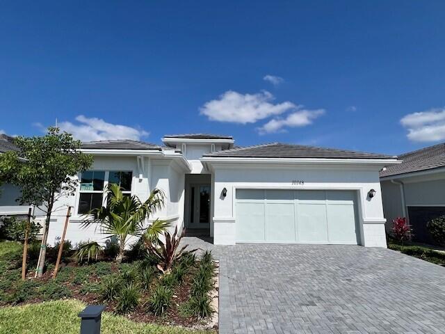 10148 Driftwood Way, Palm Beach Gardens, FL 33412 - prairie-style house with an attached garage, decorative driveway, and stucco siding
