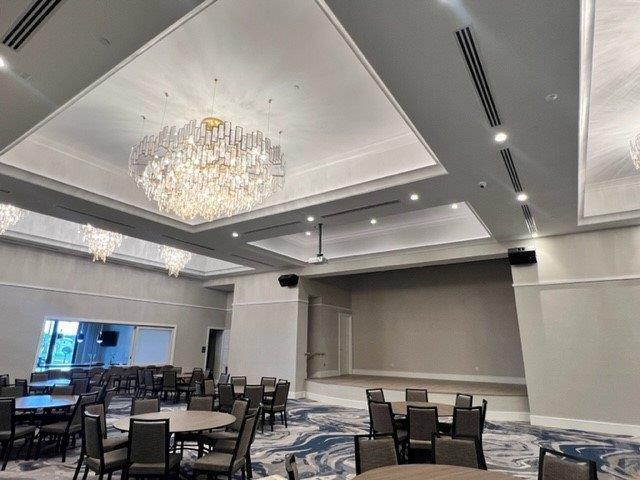 dining space featuring a raised ceiling, baseboards, visible vents, and a notable chandelier