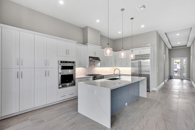 10148 Driftwood Way, Palm Beach Gardens, FL 33412 - kitchen with appliances with stainless steel finishes, a sink, under cabinet range hood, backsplash, and white cabinetry