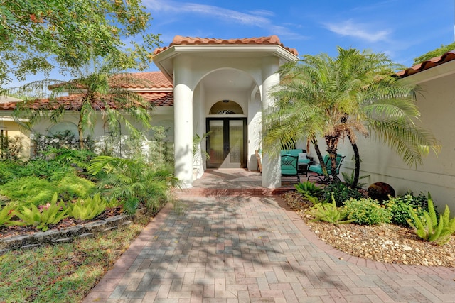 entrance to property featuring french doors, a tiled roof, and stucco siding