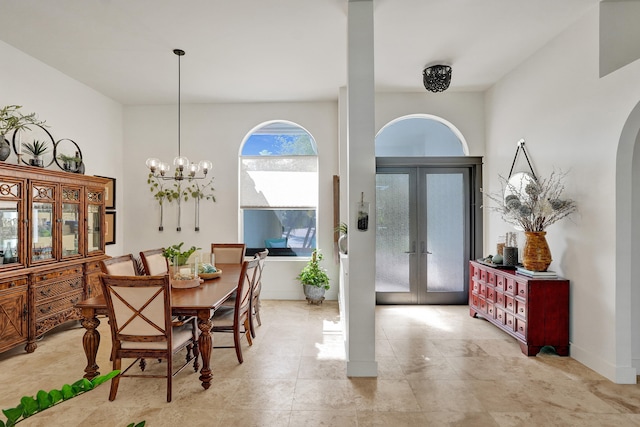 dining space with arched walkways, a chandelier, and french doors