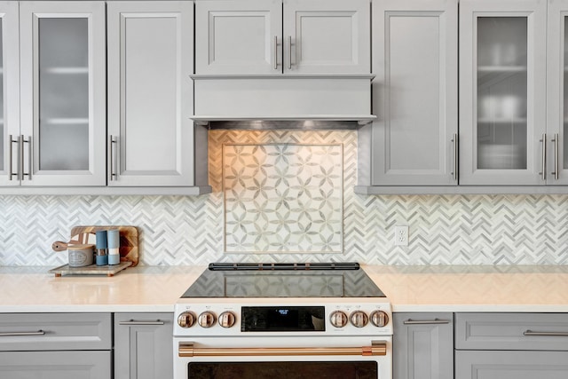 kitchen with electric range, gray cabinets, light countertops, and glass insert cabinets