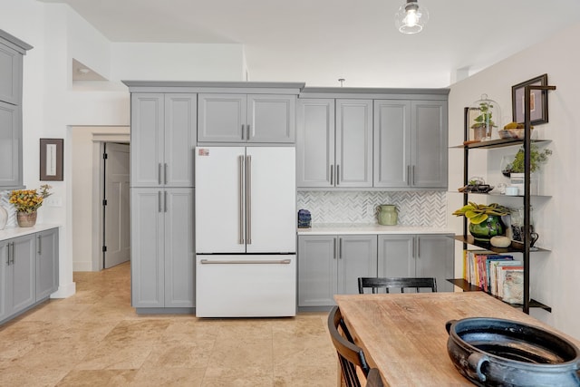 kitchen featuring white refrigerator, gray cabinets, and backsplash