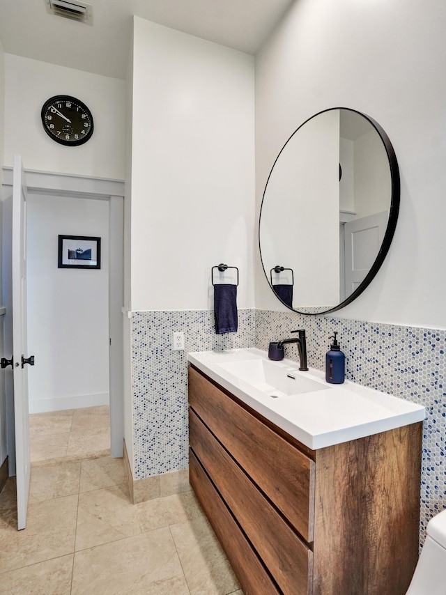 bathroom with vanity, tile patterned floors, a wainscoted wall, and tile walls