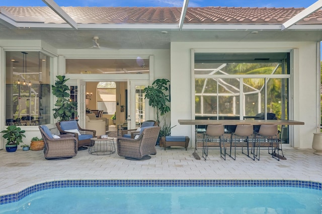 swimming pool with glass enclosure, a patio area, an outdoor living space, and an outdoor bar
