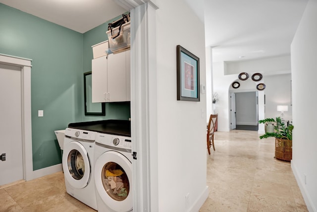 laundry area featuring separate washer and dryer, cabinet space, and baseboards