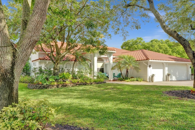 mediterranean / spanish home with a tiled roof, a front yard, stucco siding, and an attached garage