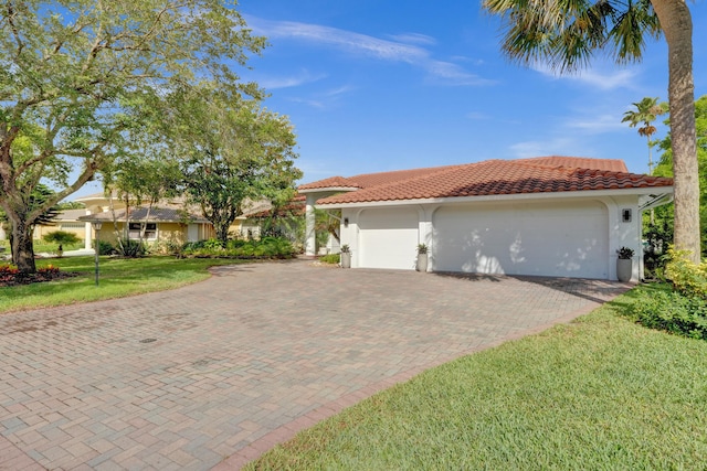 mediterranean / spanish-style home with stucco siding, a garage, decorative driveway, a tiled roof, and a front lawn